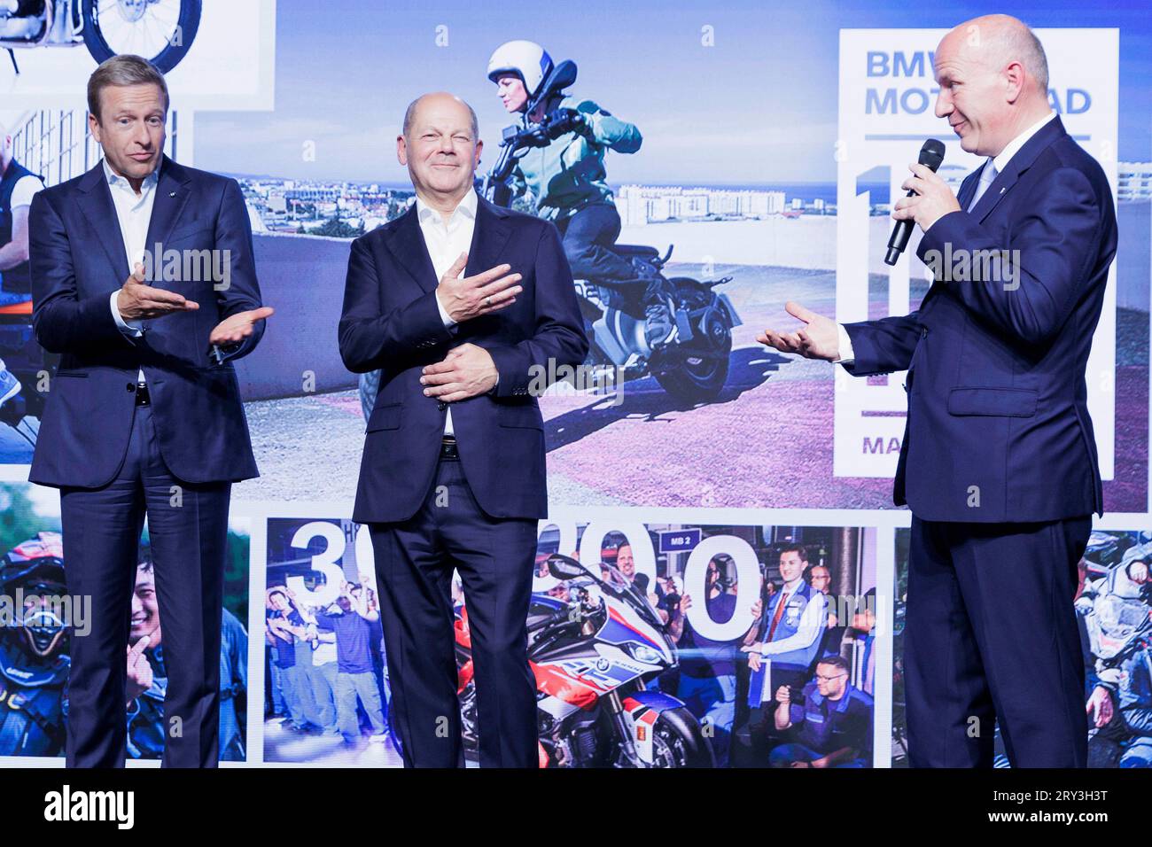 Berlin, Deutschland. September 2023 28. Oliver Zipse (l-r), Vorsitzender des Vorstands der BMW AG, Bundeskanzler Olaf Scholz (SPD) und Kai Wegner (CDU), Regierender Bürgermeister von Berlin, lachen auf der Bühne beim 100-jährigen Jubiläum von BMW Motorcycle im BMW Motorradwerk. Quelle: Carsten Koall/dpa/Alamy Live News Stockfoto