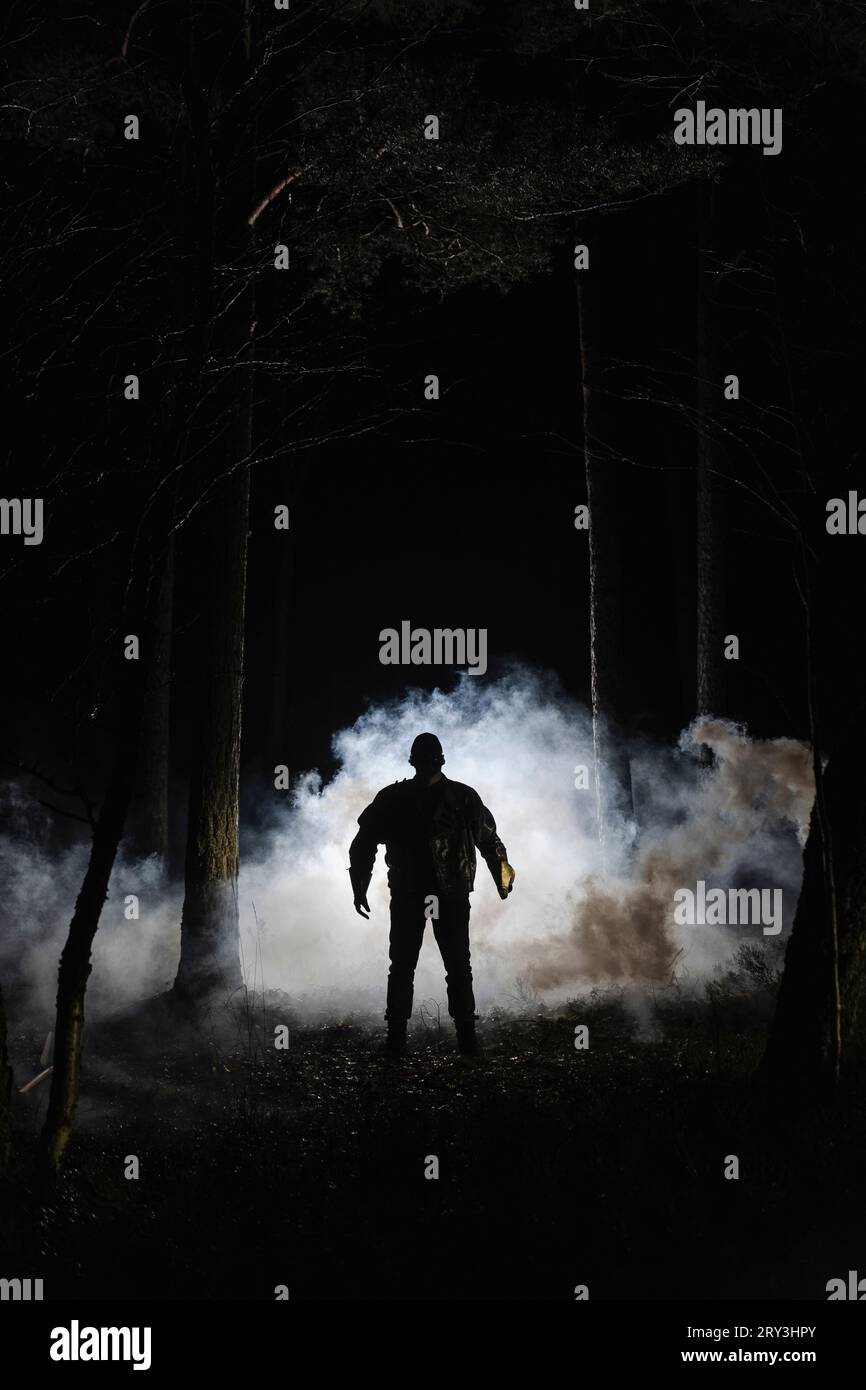 Silhouette Dämon, der nachts vor Rauch im Wald steht Stockfoto