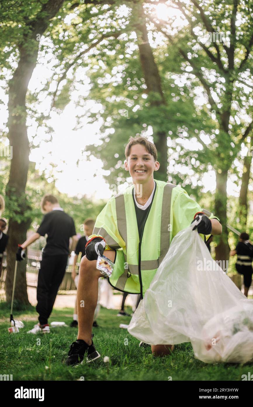 Porträt eines lächelnden Teenagers, der Plastik im Müllsack sammelt Stockfoto