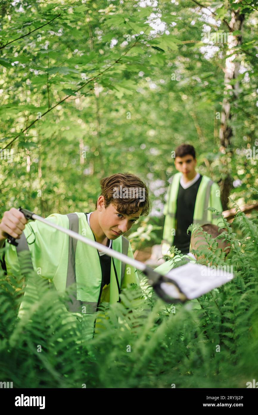 Teenager-Junge, der Plastikmüll aus der Pflanze sammelt Stockfoto
