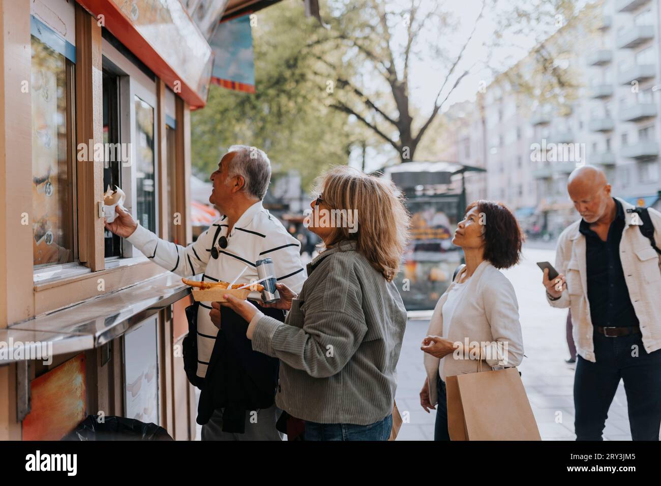 Männliche und weibliche Seniorenfreunde kaufen auf der Straße einen Lebensmittelladen Stockfoto