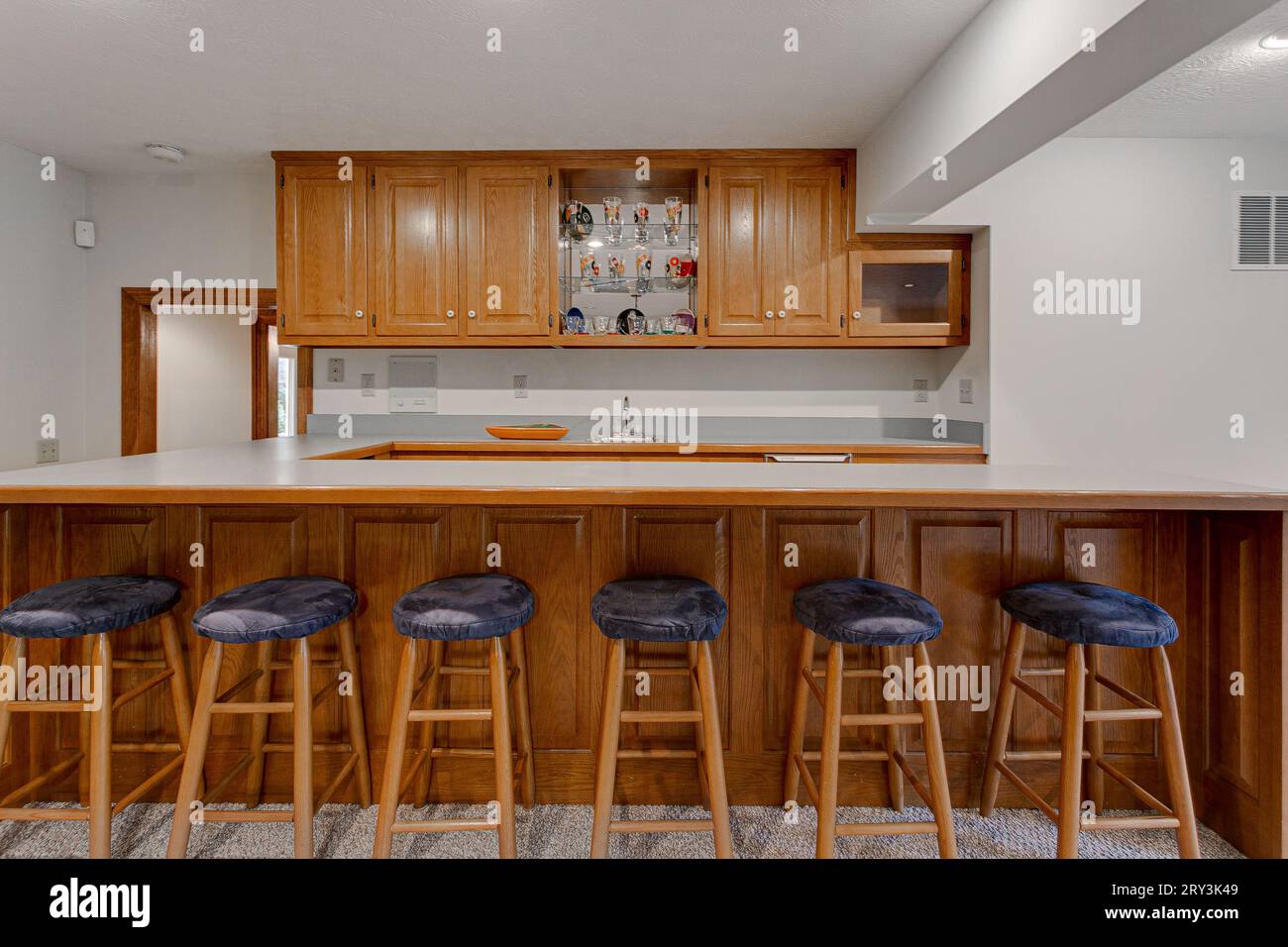 Kochnische im Barstil mit sechs Barstempeln und Long Island Counter. Holzschränke und minimales Styling Stockfoto