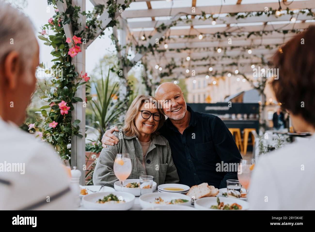 Porträt eines lächelnden älteren Mannes mit Arm um eine ältere Freundin, die im Restaurant sitzt Stockfoto