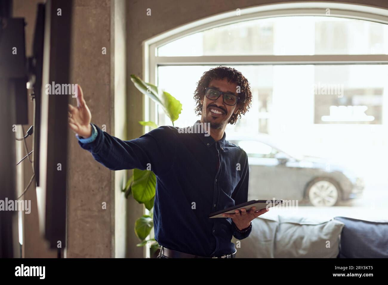 Glücklicher Geschäftsmann mit Gesten für ein digitales Tablet im kreativen Büro Stockfoto