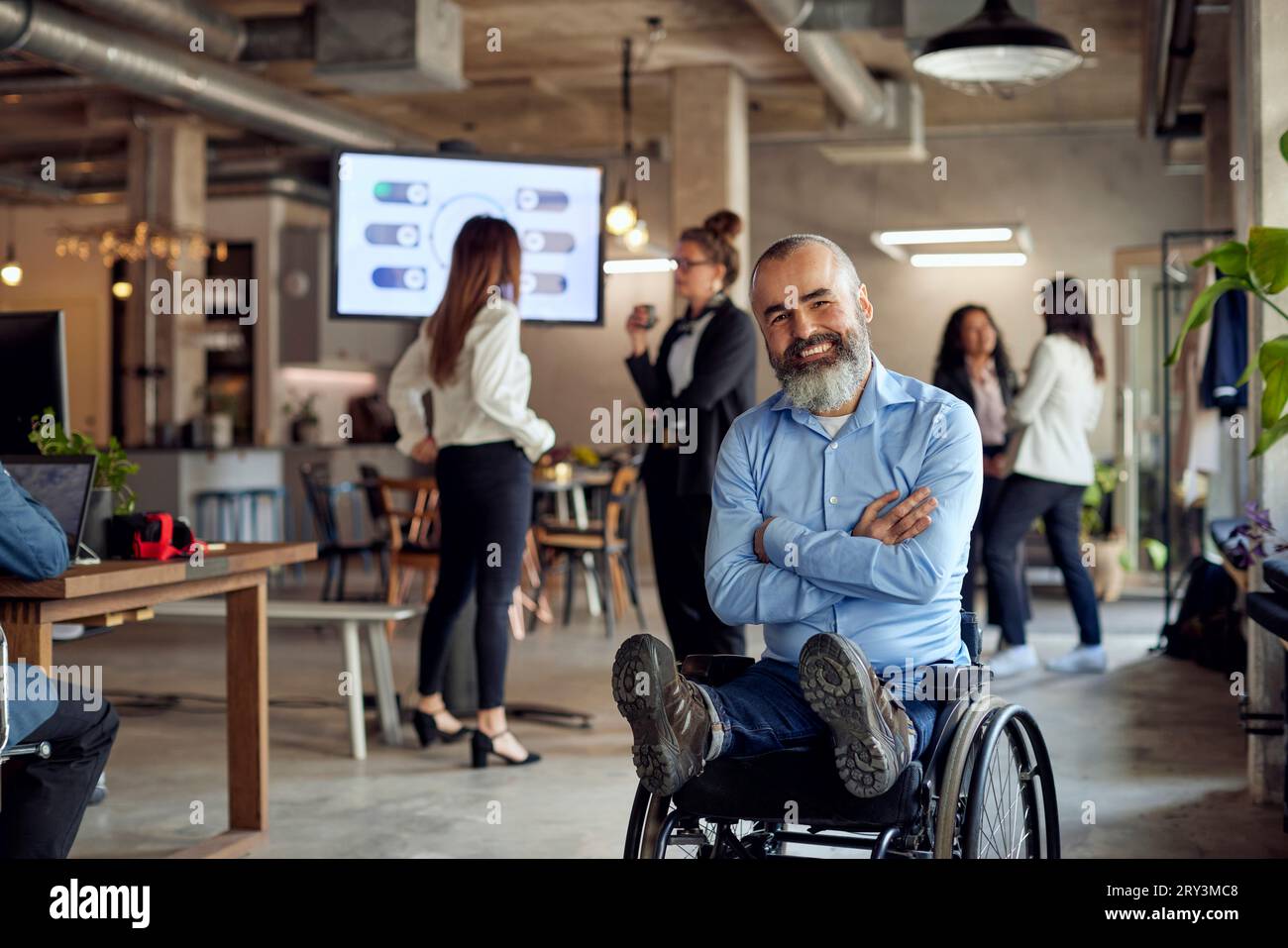 Porträt eines glücklichen bärtigen Geschäftsmannes mit Behinderung im Rollstuhl im Büro Stockfoto