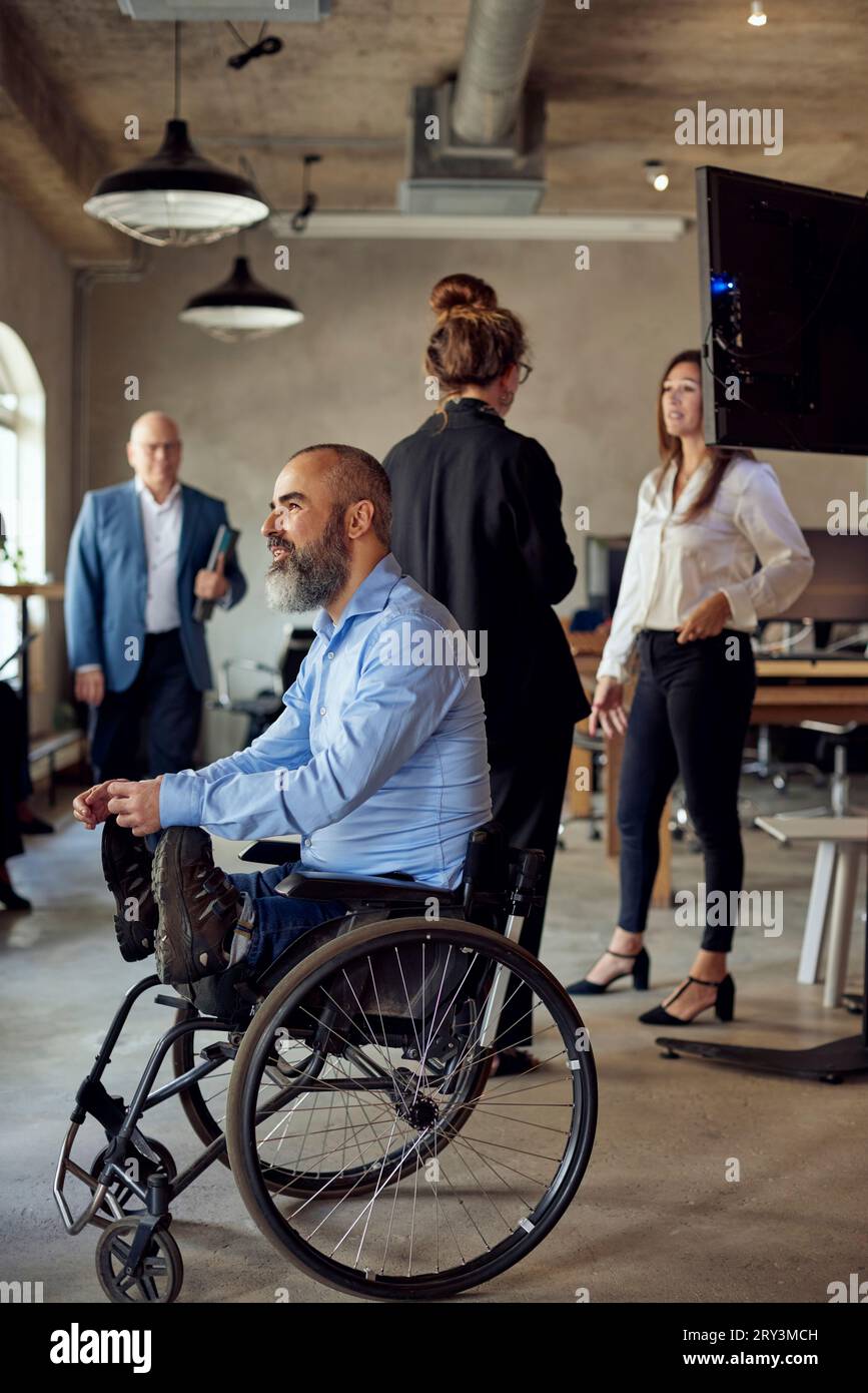Behinderter Geschäftsmann in der Nähe von Kollegen im Kreativbüro Stockfoto