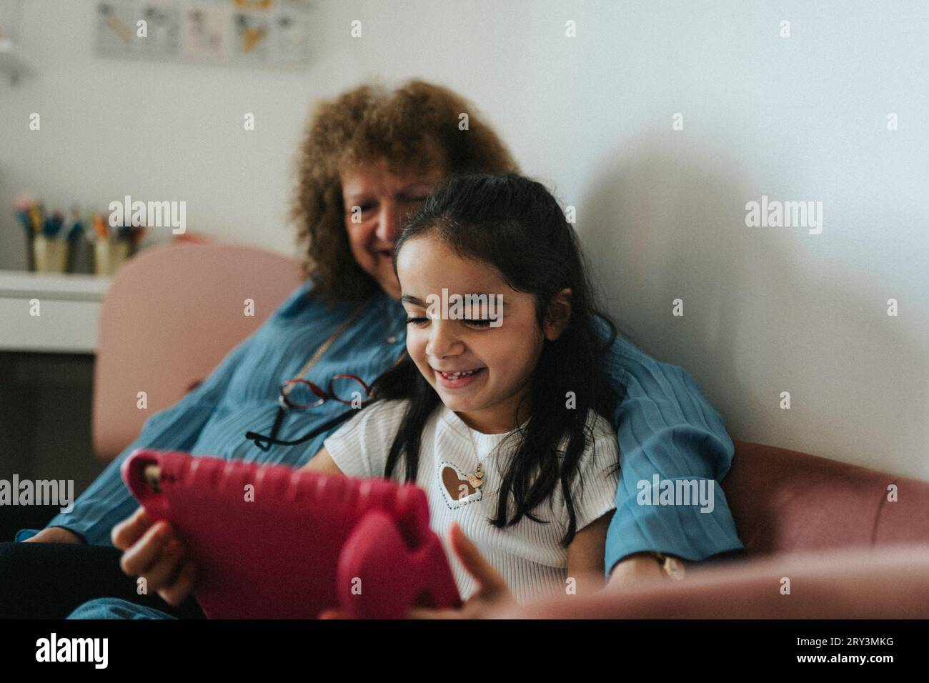 Lächelndes Mädchen, das ein digitales Tablet mit Großmutter zu Hause benutzt Stockfoto