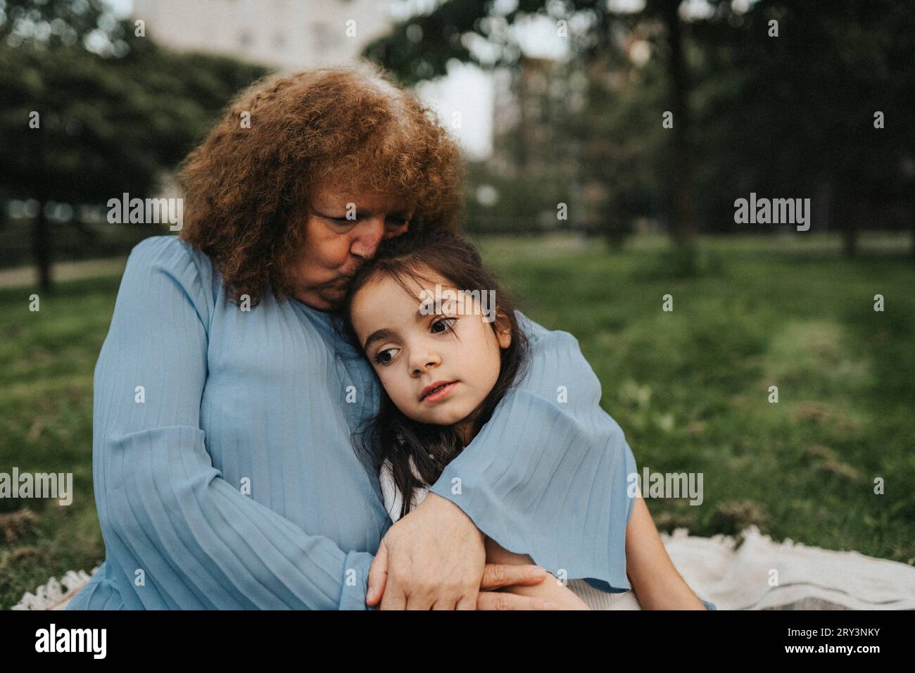 Eine ältere Frau küsst Enkelin im Park Stockfoto