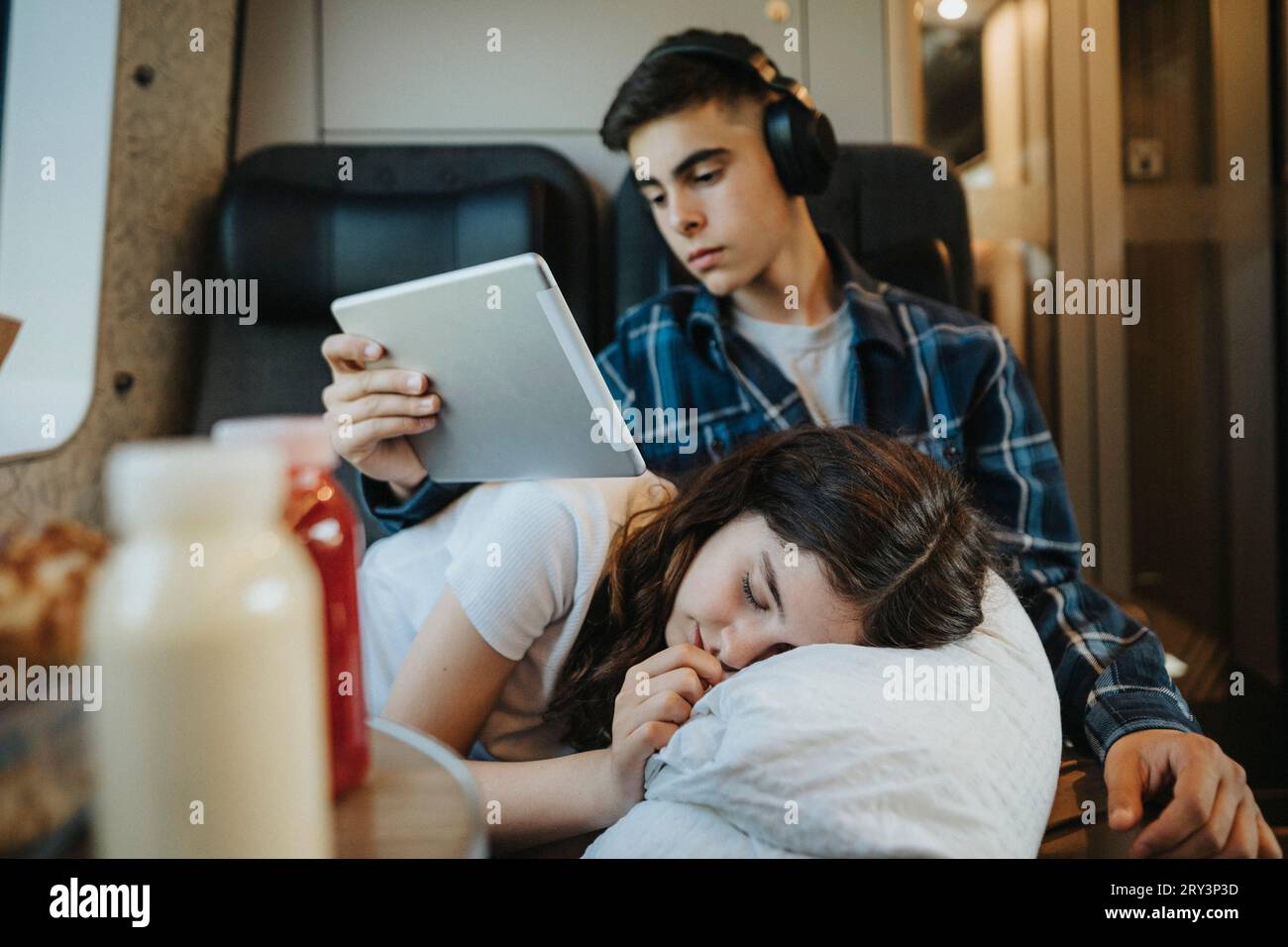 Junge mit Tablet-PC und Schwester, die im Zug ein Nickerchen macht Stockfoto