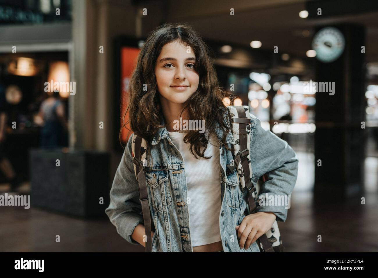 Porträt eines lächelnden Mädchens, das eine Jeansjacke trägt, während er auf der Station steht Stockfoto