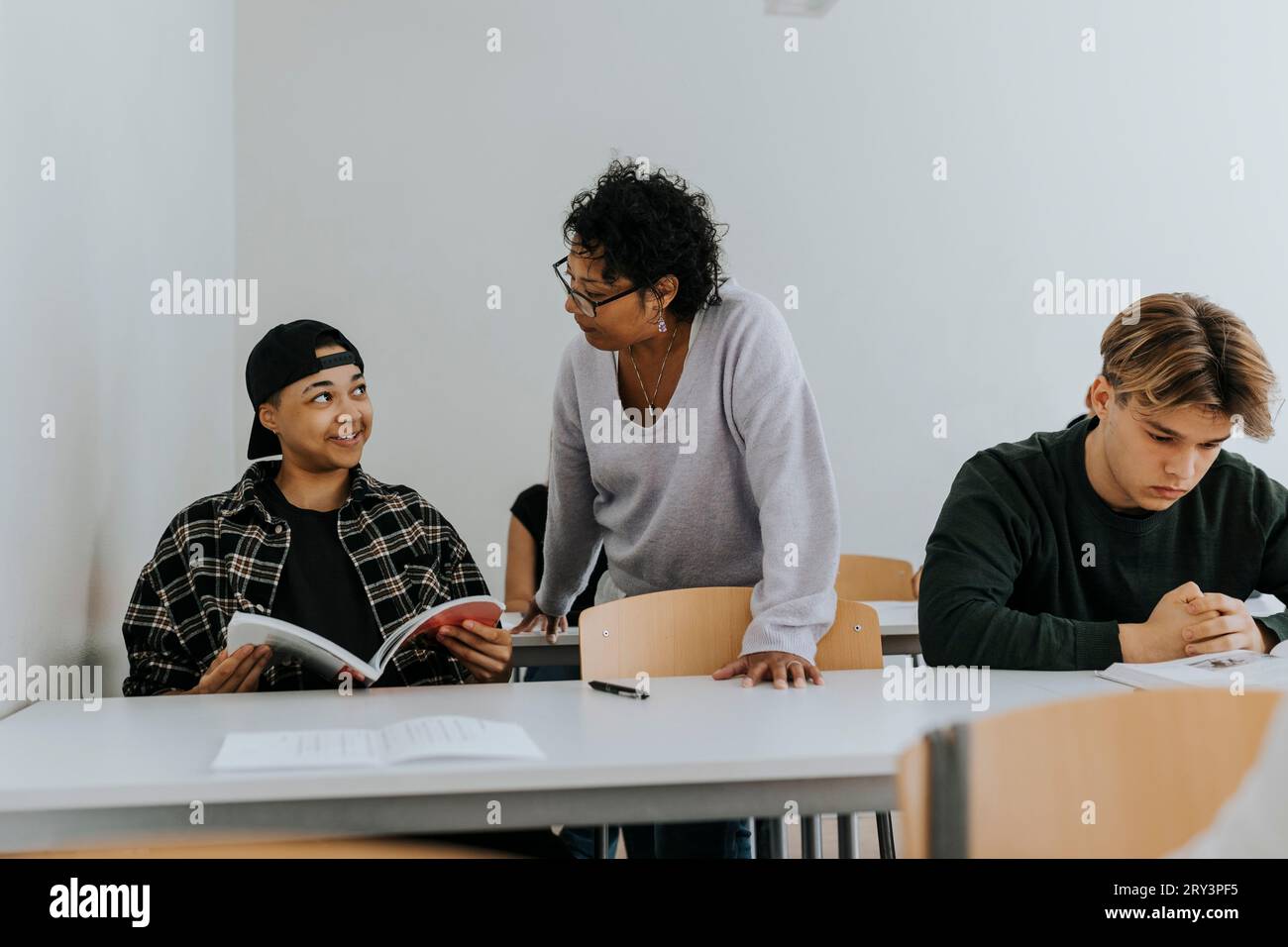 Der Lehrer sieht einen lächelnden männlichen Schüler im Klassenzimmer Stockfoto