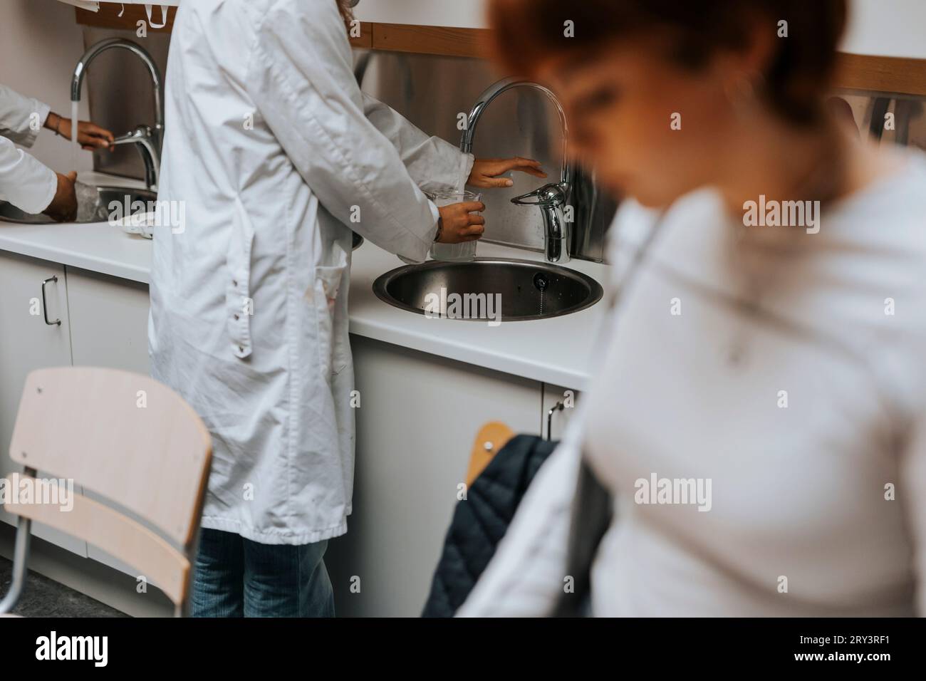 Mittelteil einer jungen Studentin, die im Waschbecken im Wissenschaftslabor wäscht Stockfoto