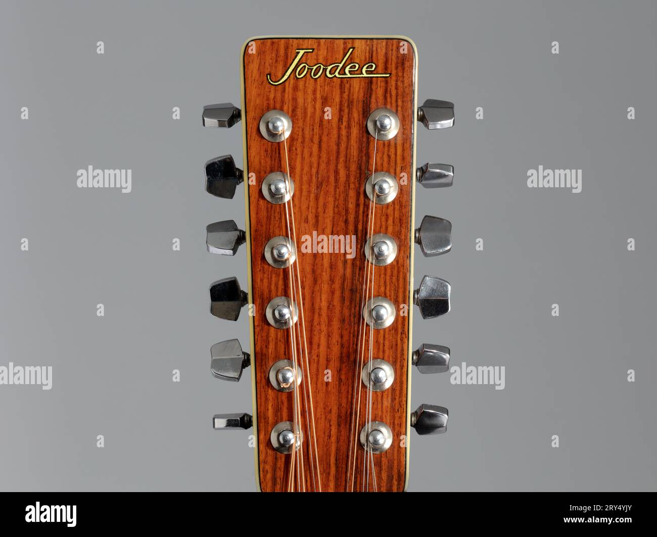 Nahaufnahme des Joodee akustischen 12-saitigen Gitarrenkopfstocks auf grauem Hintergrund Stockfoto