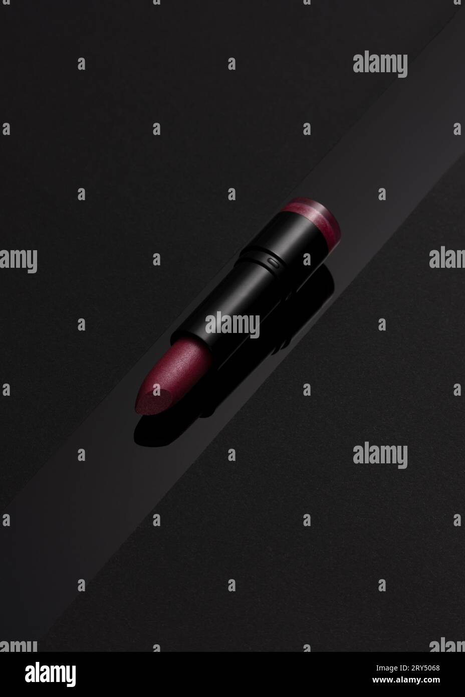 Rosafarbener Lippenstift auf mattschwarzem Hintergrund mit schwarzem Glanzstreifen Stockfoto