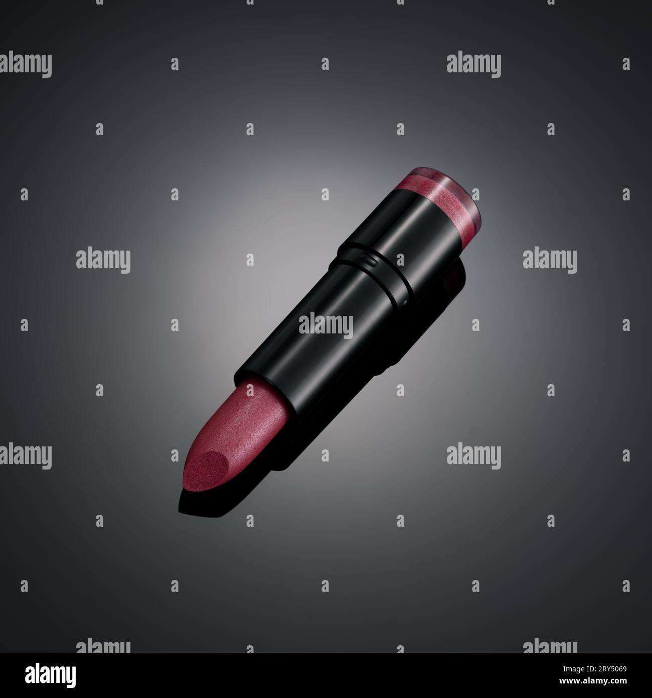 Pinkfarbener Lippenstift auf mattschwarzem Hintergrund mit einer zentralen Lichtkugel Stockfoto