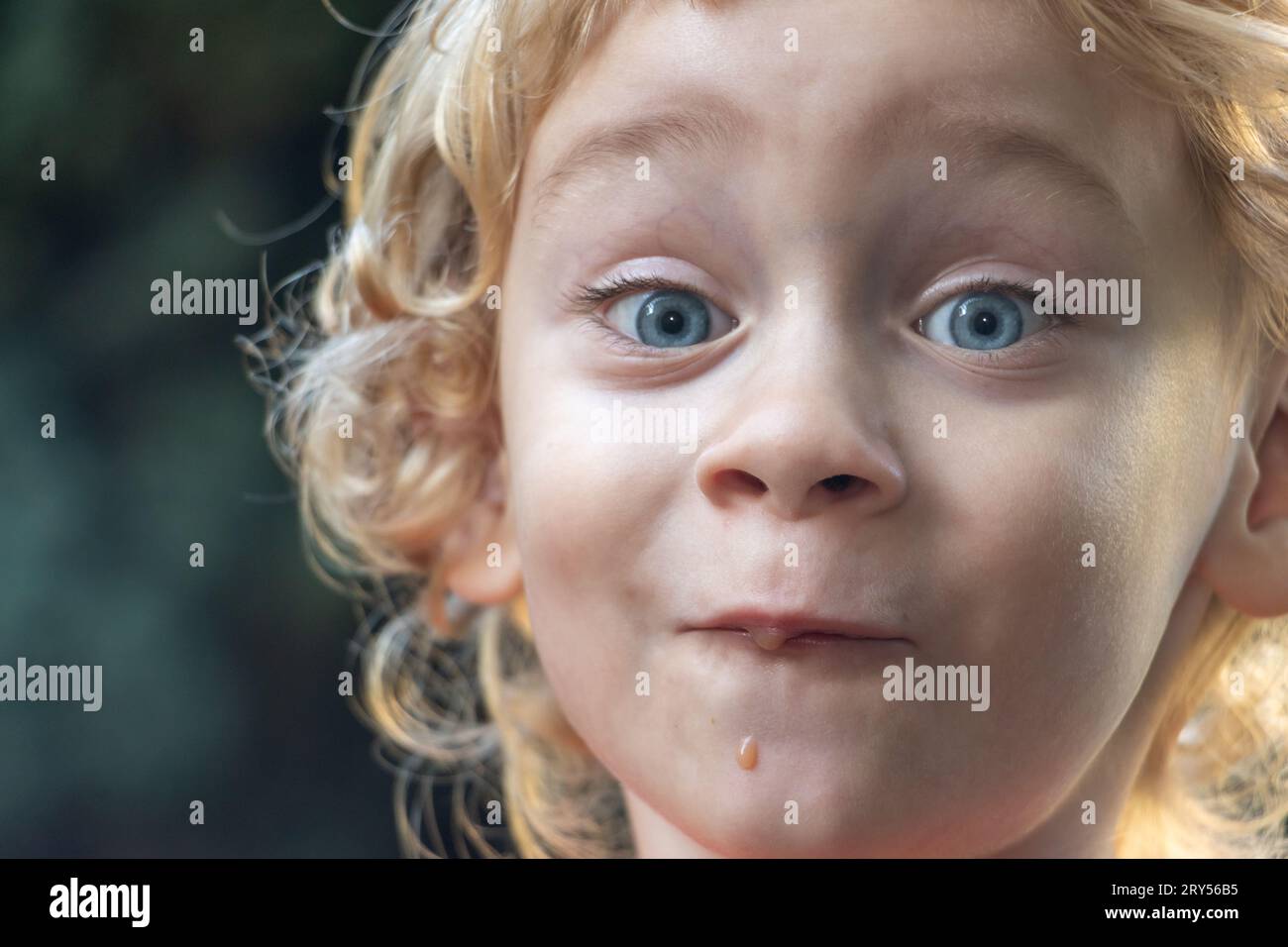 Porträt eines glücklichen Jungen mit Gesichtsausdruck nach Verkostung eines süßen flüssigen Essens Stockfoto