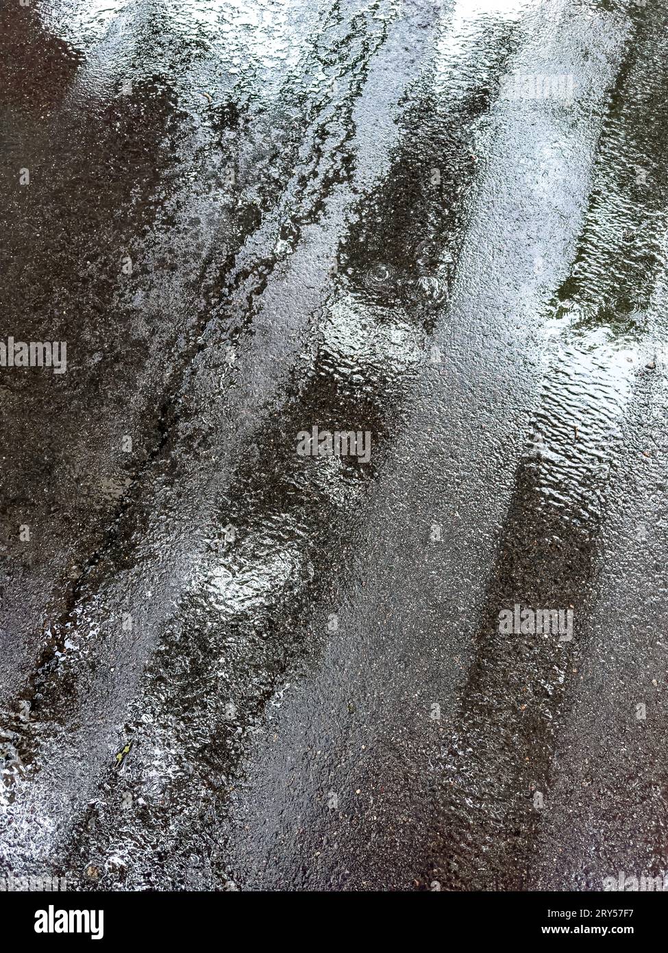 Textur der nassen Asphaltstraße nach Regen. Regnerischer Tag in der Stadt. Stockfoto