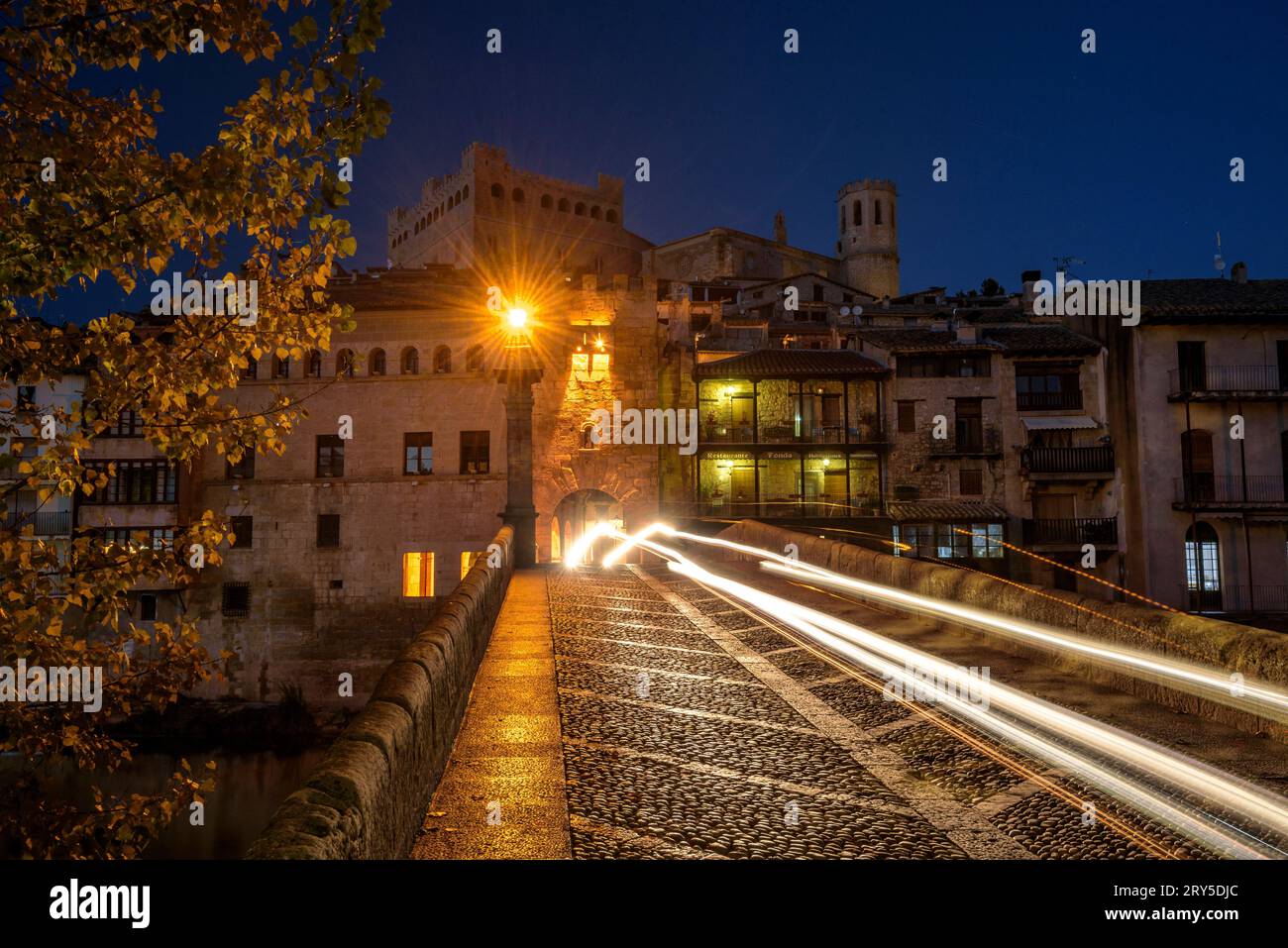 Burg und Kirche von Valderrobres, beleuchtet zur blauen Stunde und in der Nacht, von der Brücke über den Fluss Matarraña (Teruel, Aragon, Spanien) aus gesehen Stockfoto