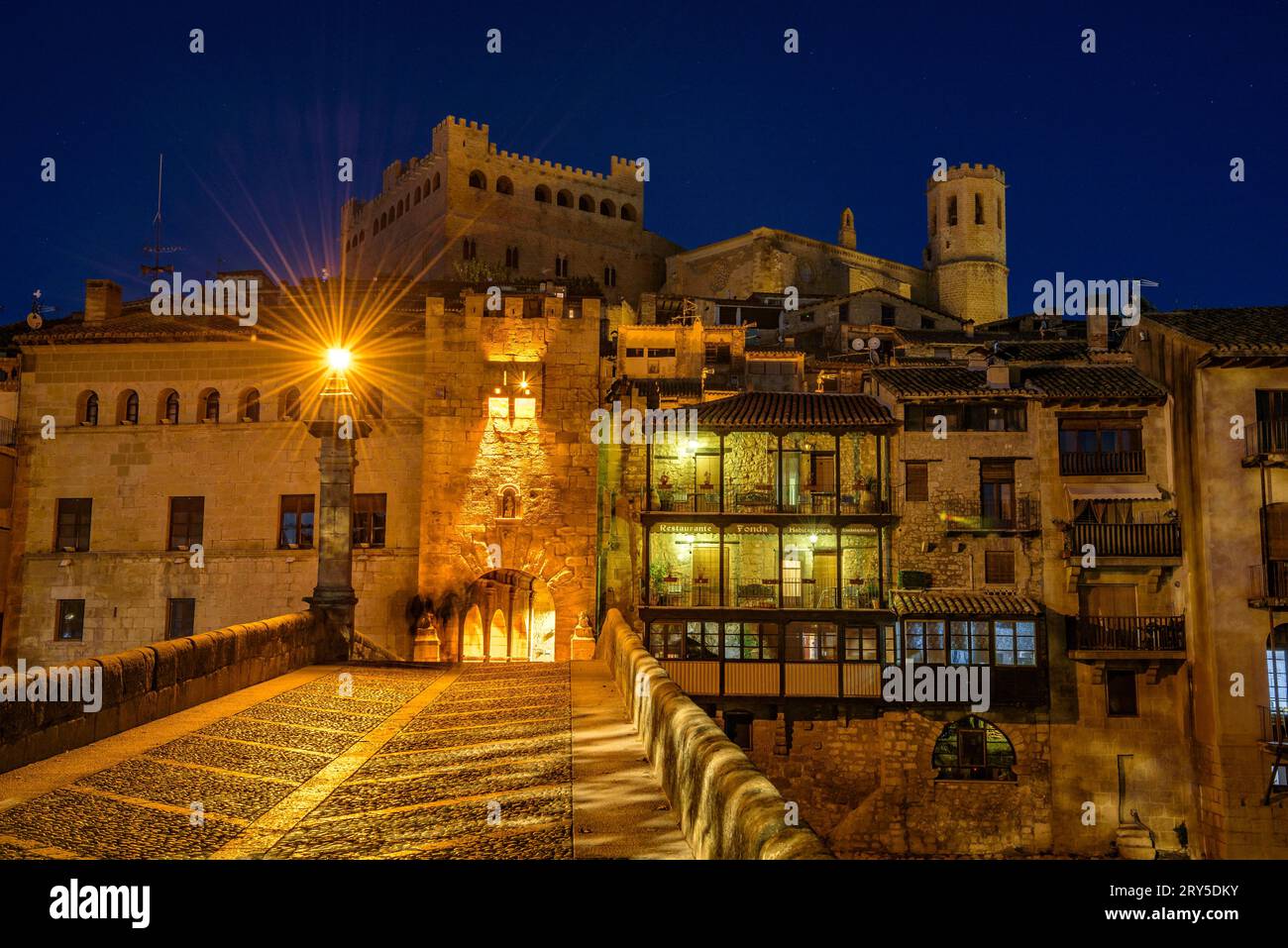 Burg und Kirche von Valderrobres, beleuchtet zur blauen Stunde und in der Nacht, von der Brücke über den Fluss Matarraña (Teruel, Aragon, Spanien) aus gesehen Stockfoto