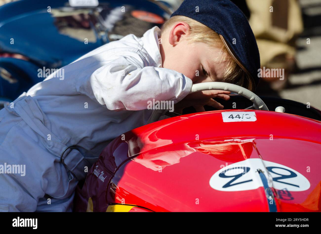 Ein kleiner Junge, der sich darauf vorbereitet, im Settrington Cup beim Goodwood Revival 2016 in einem Austin J40 Peddle Car zu fahren. Vor dem Rennen in das Cockpit des Fahrzeugs blicken Stockfoto