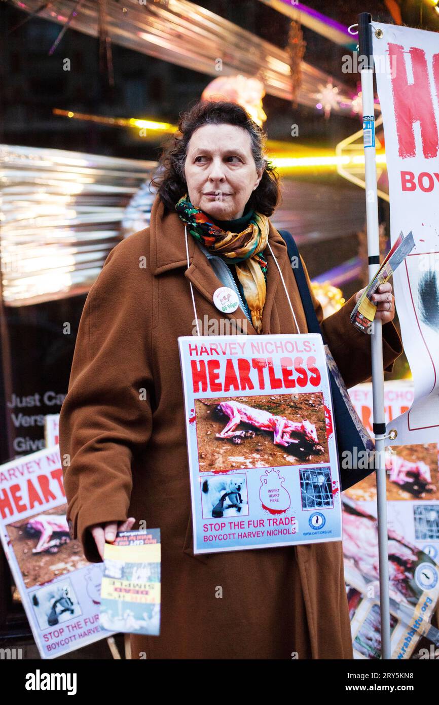 Tierschutzproteste vor Harvey Nichols London 30. November 2013 - ältere Dame im langen braunen Mantel mit herzlosem Harvey Nichols-Zeichen Stockfoto