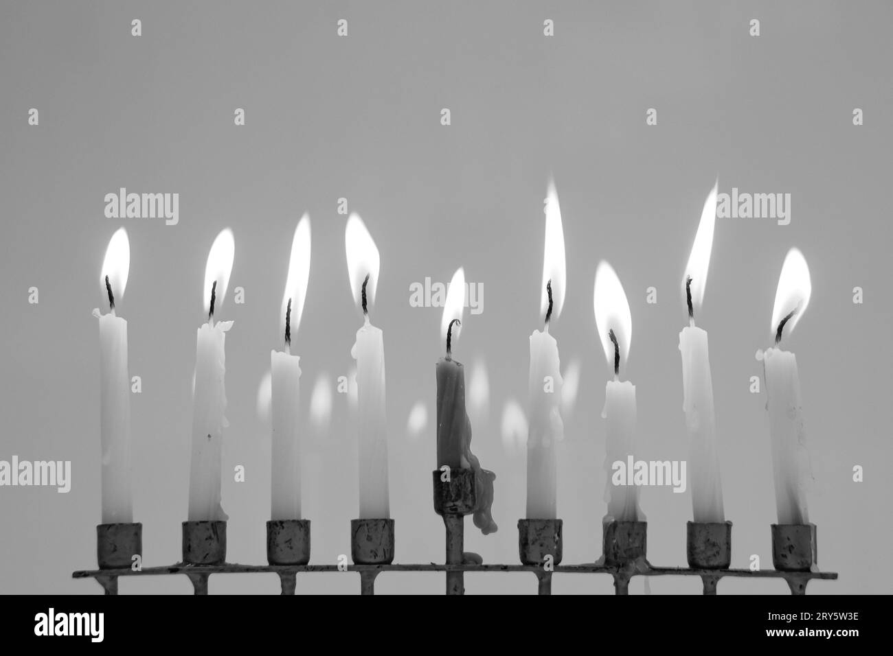 Schwarz-weiß volle Menora am letzten Abend von Hanukka. Alle neun Kerzen leuchten auf und reflektieren im Hintergrund. Urlaubskonzept Stockfoto