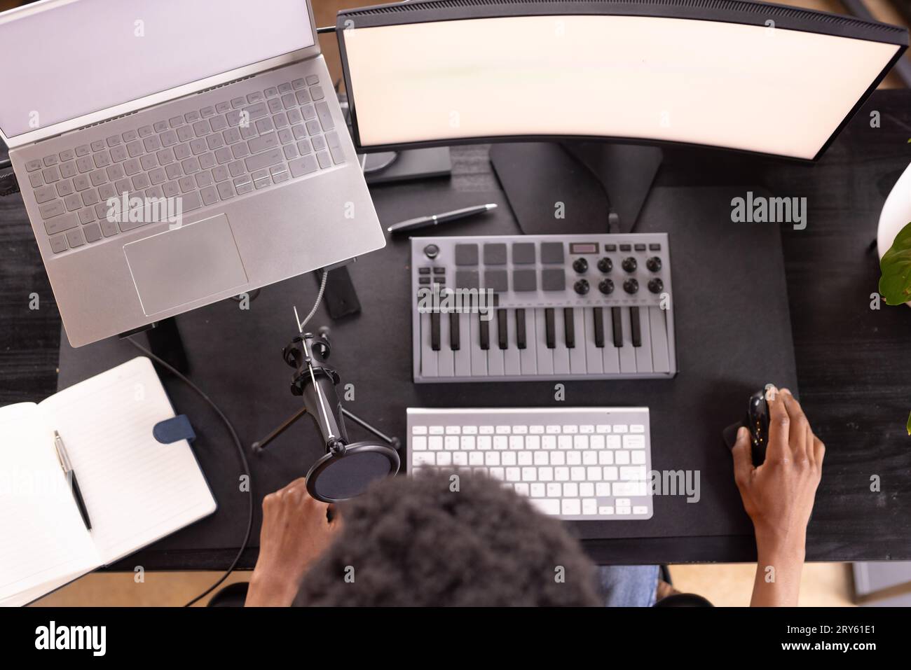 Overhead eines afroamerikanischen Mannes, der Live-Podcasts mit Laptop, Computer und Tastatur zu Hause macht Stockfoto