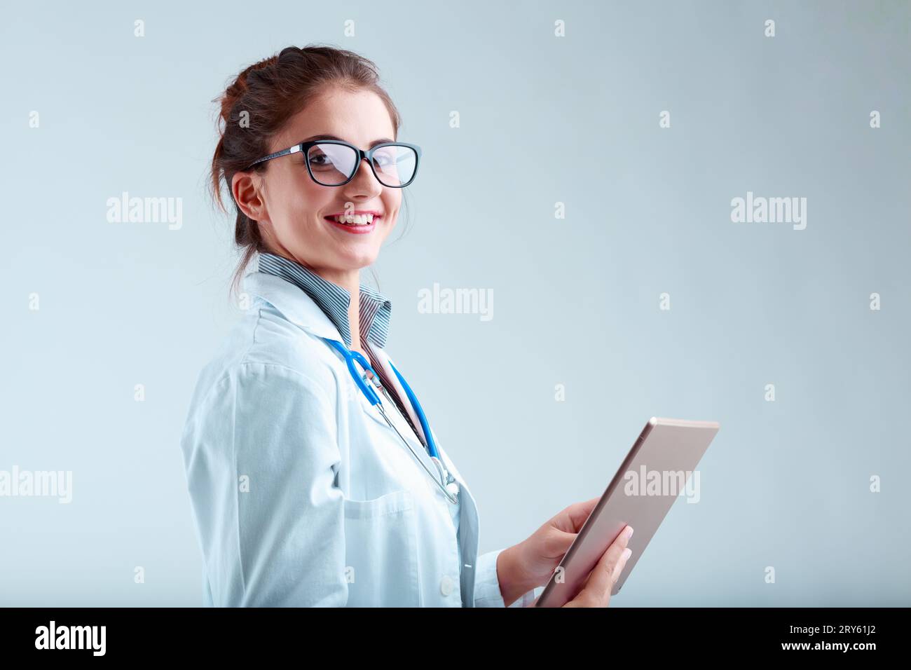 Oung Forscherin in Labormantel und Brille, lächelnd und blickend von ihrem Tablet, bietet sachliche Klarheit und Anleitung für fundierte Entscheidungen Stockfoto