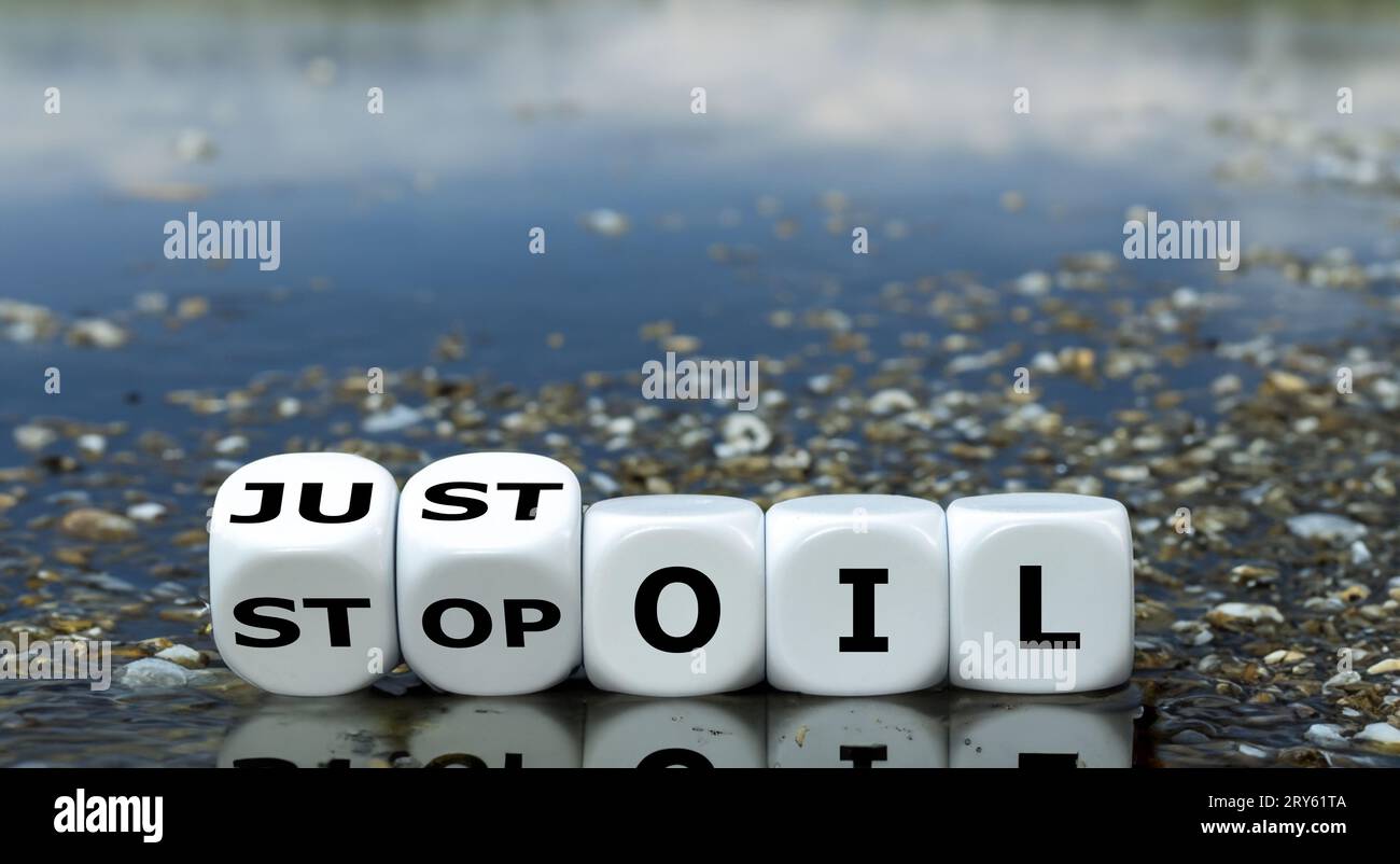 Würfel bilden den Ausdruck „nur Öl stoppen“ vor einem See voller Öl. Stockfoto