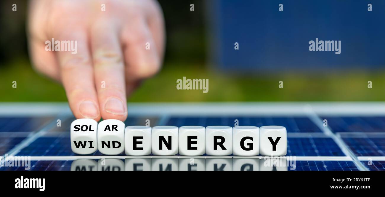 Würfel bilden den Ausdruck „Windenergie“ und „Solarenergie“ auf einem Sonnenkollektor. Stockfoto
