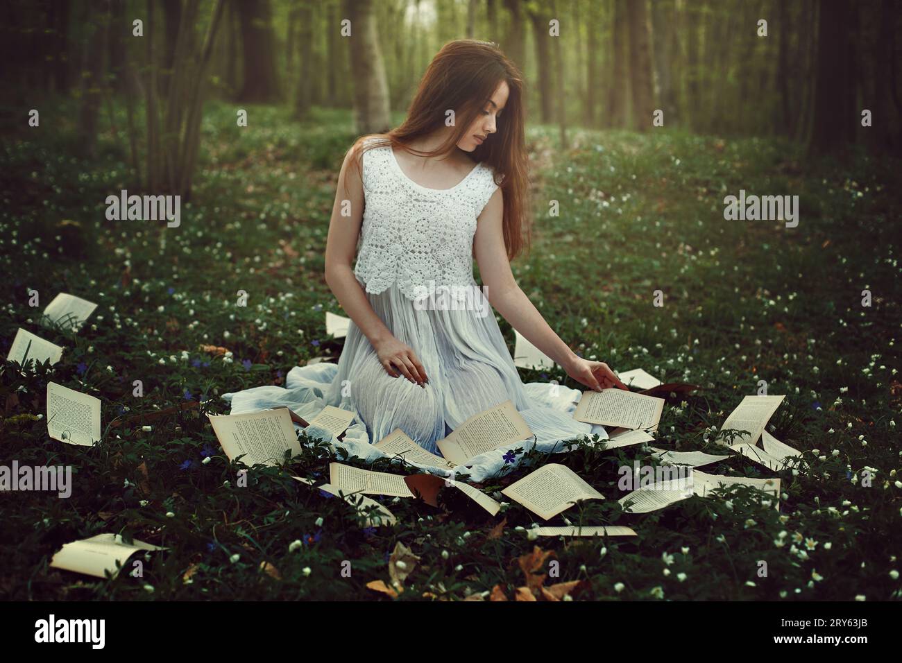 Unschuldiges Mädchen im Märchenwald unter Buchseiten Stockfoto