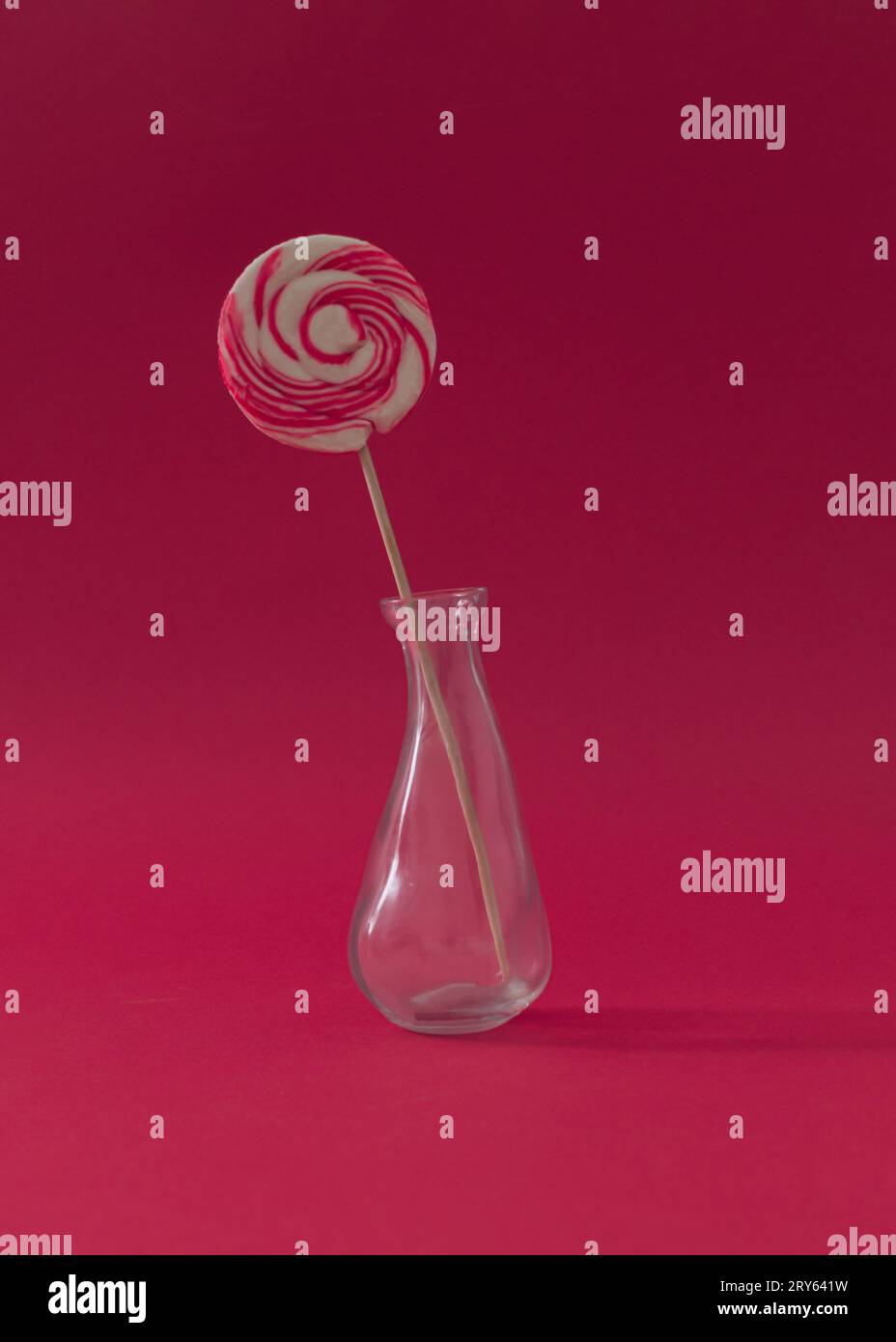 Lutscher als Blume in einer Vase vor rotem Hintergrund. Sommerbonbons-Konzept. Kreative, süße Idee. Stockfoto