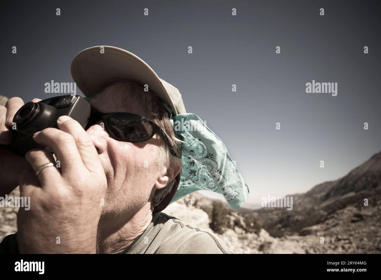 Ein reifer Mann in den Bergen, der eine Kamera im Gesicht hält. (Releasecode: Rrk mr42) Stockfoto