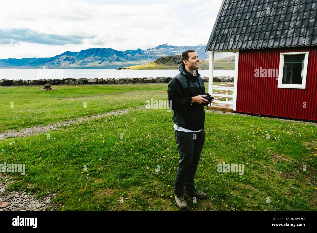 Der Mann fliegt Drohne über Fjorde mit grünem Gras und Bergen Stockfoto