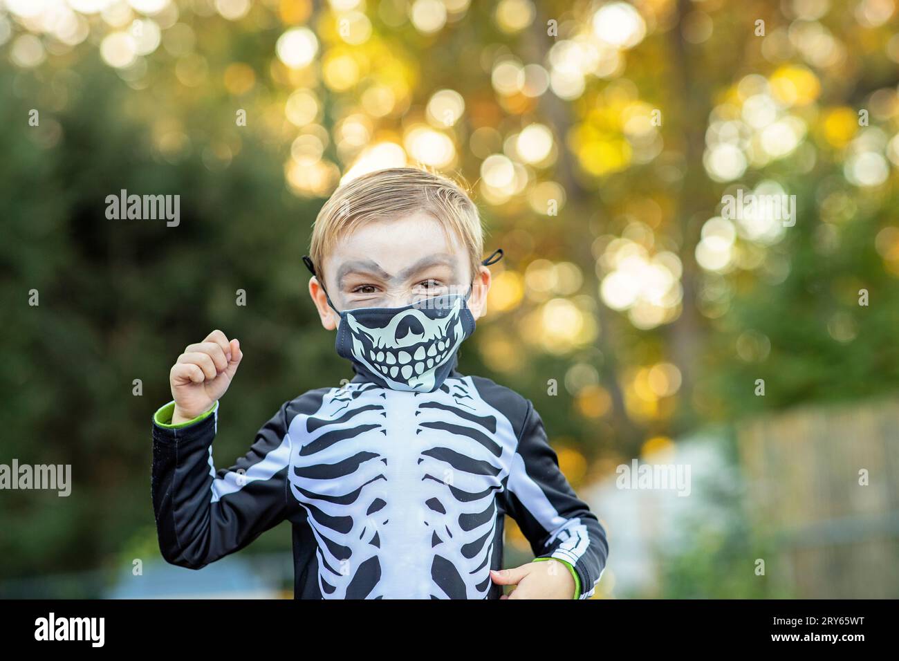 Kleiner Junge im Skelett Halloween Kostüm, im Bokeh von Herbstblättern. Stockfoto