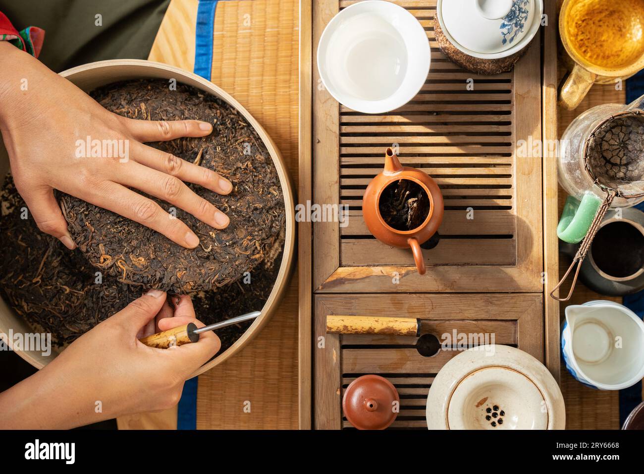 Frau, die fermentierten Tee zubereitet, umgeben von Töpfen und Tassen Stockfoto