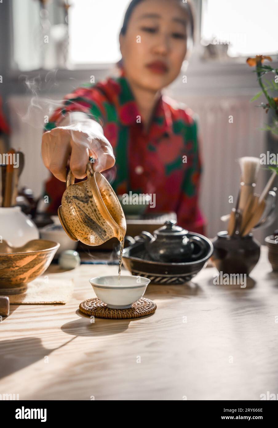 Koreanerin, die Tee in Eine Tasse auf dem Tisch gießt Stockfoto