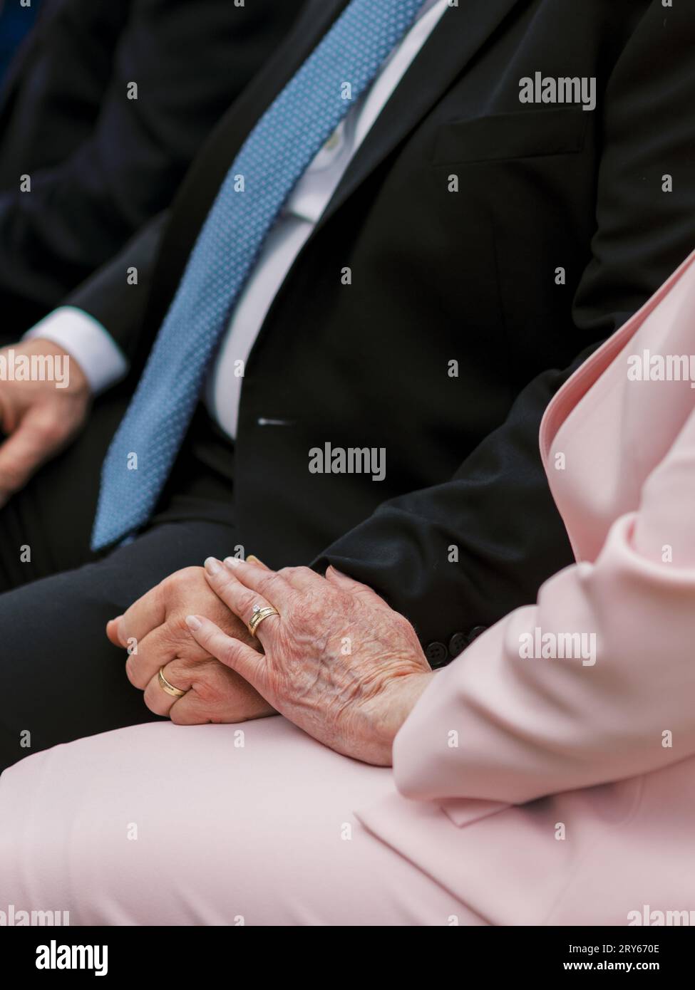 Ein älteres Paar hält Hände, trägt goldene Eheringe, kleidet sich Stockfoto