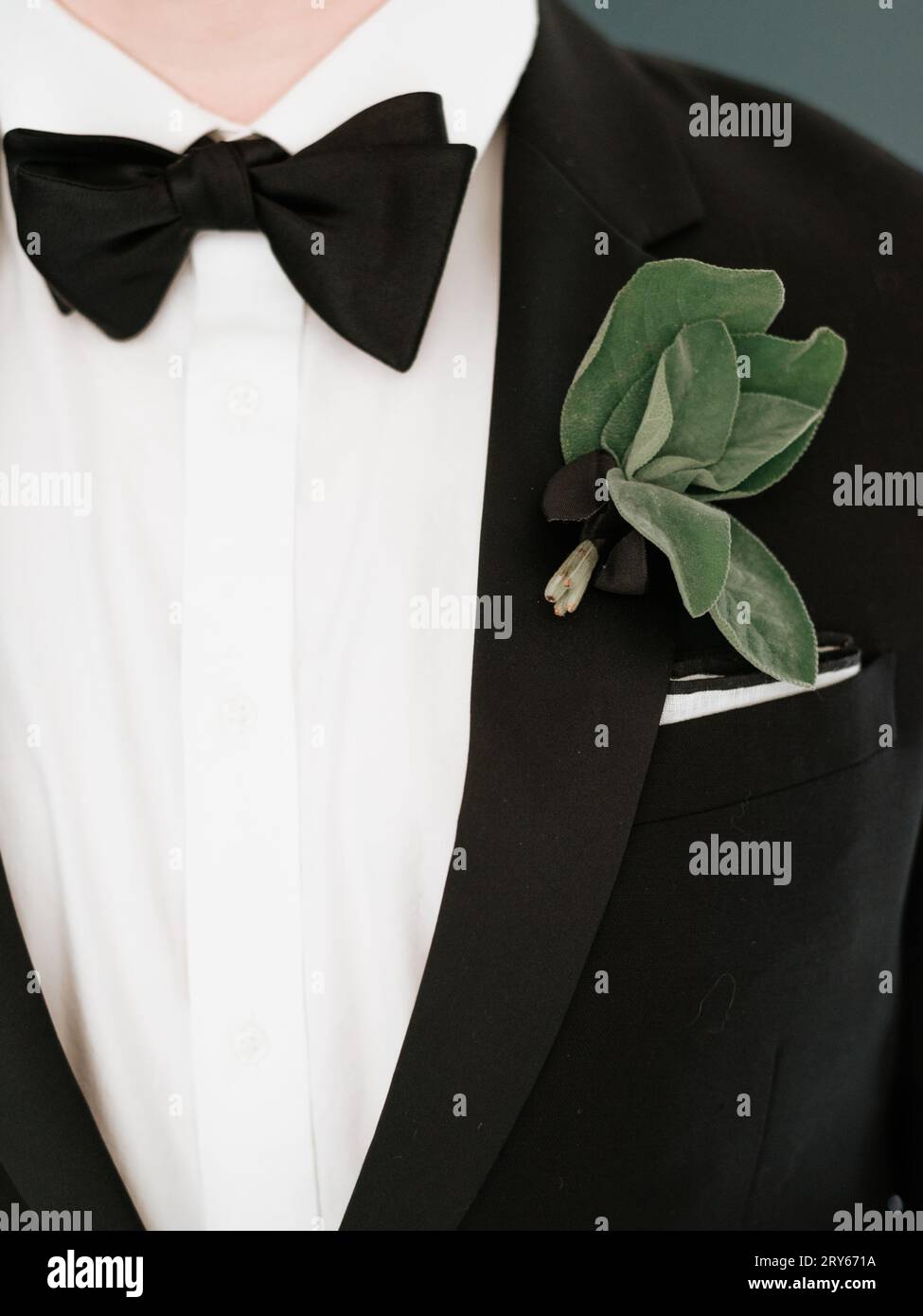 Nahaufnahme eines schwarzen Krawattentuchs eines Mannes mit einer Salbeiblatt-Boutonniere Stockfoto