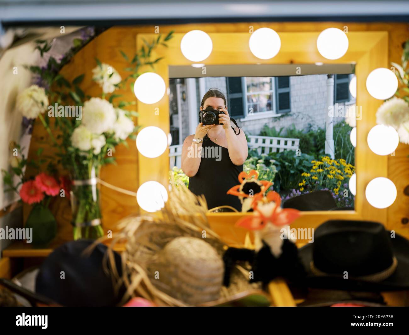 Frau, die ihr Spiegelbild in einem Spiegel der Fotokabine festnimmt Stockfoto