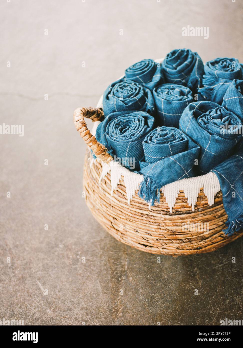 Rustikaler Korb mit gerollten blauen Decken Stockfoto