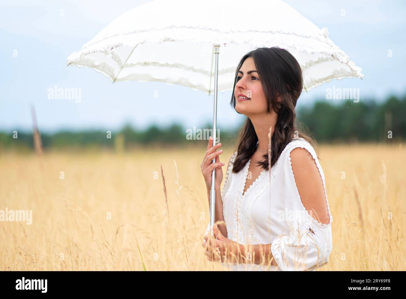 Junge hübsche Frau mit Regenschirm und weißem Kleid Stockfoto