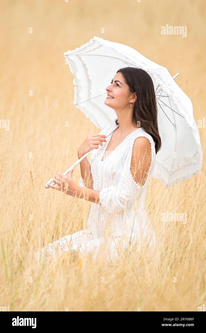 Romantische Szene mit einer jungen, hübschen Verlobten mit Regenschirm und Kleid Stockfoto