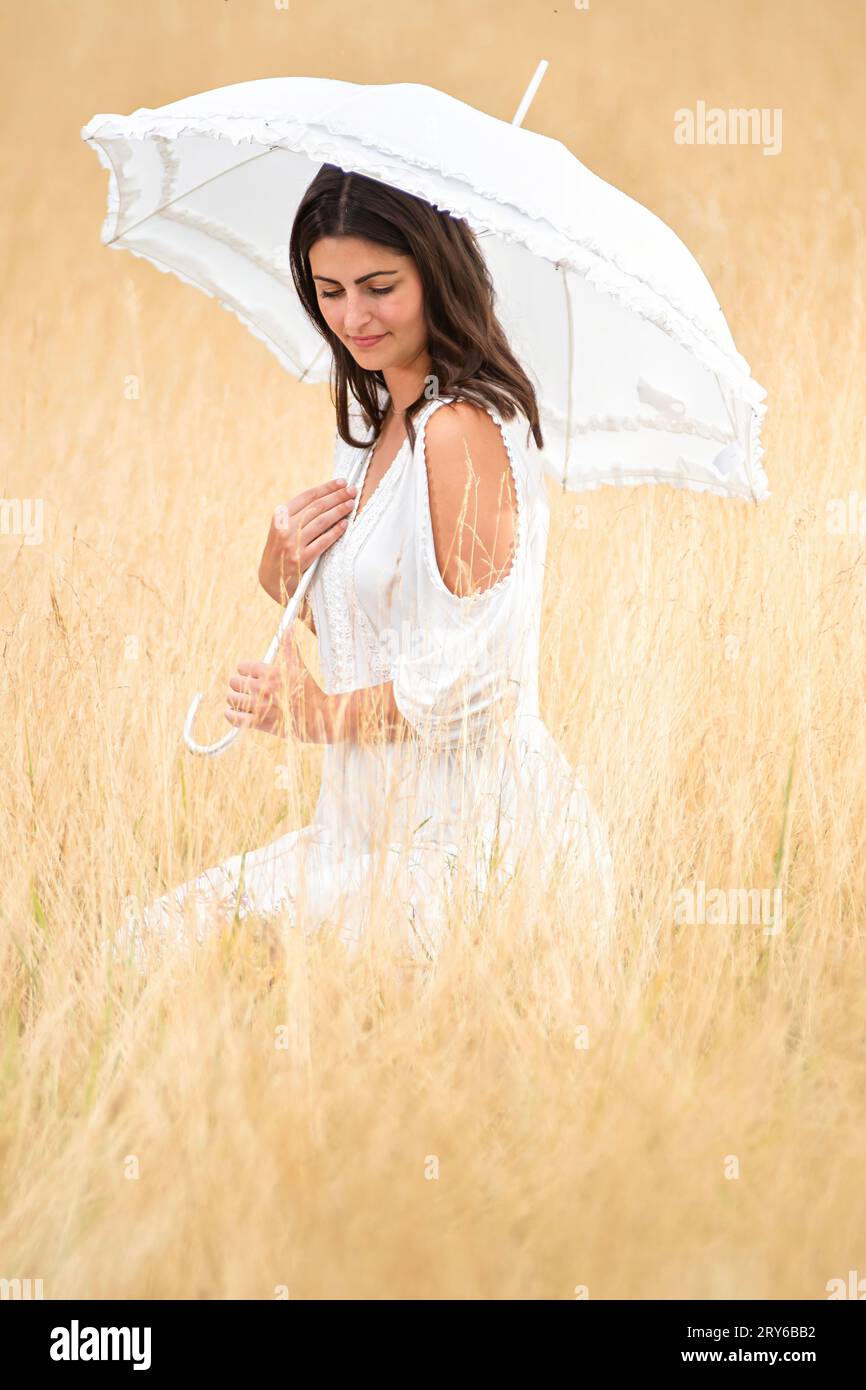 Nachdenkliche Frau mit Regenschirm und Kleid Stockfoto
