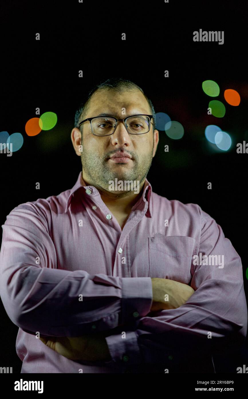 Männerporträt mit Hemden und Brille mit verschwommenen Lichtern im Hintergrund Stockfoto