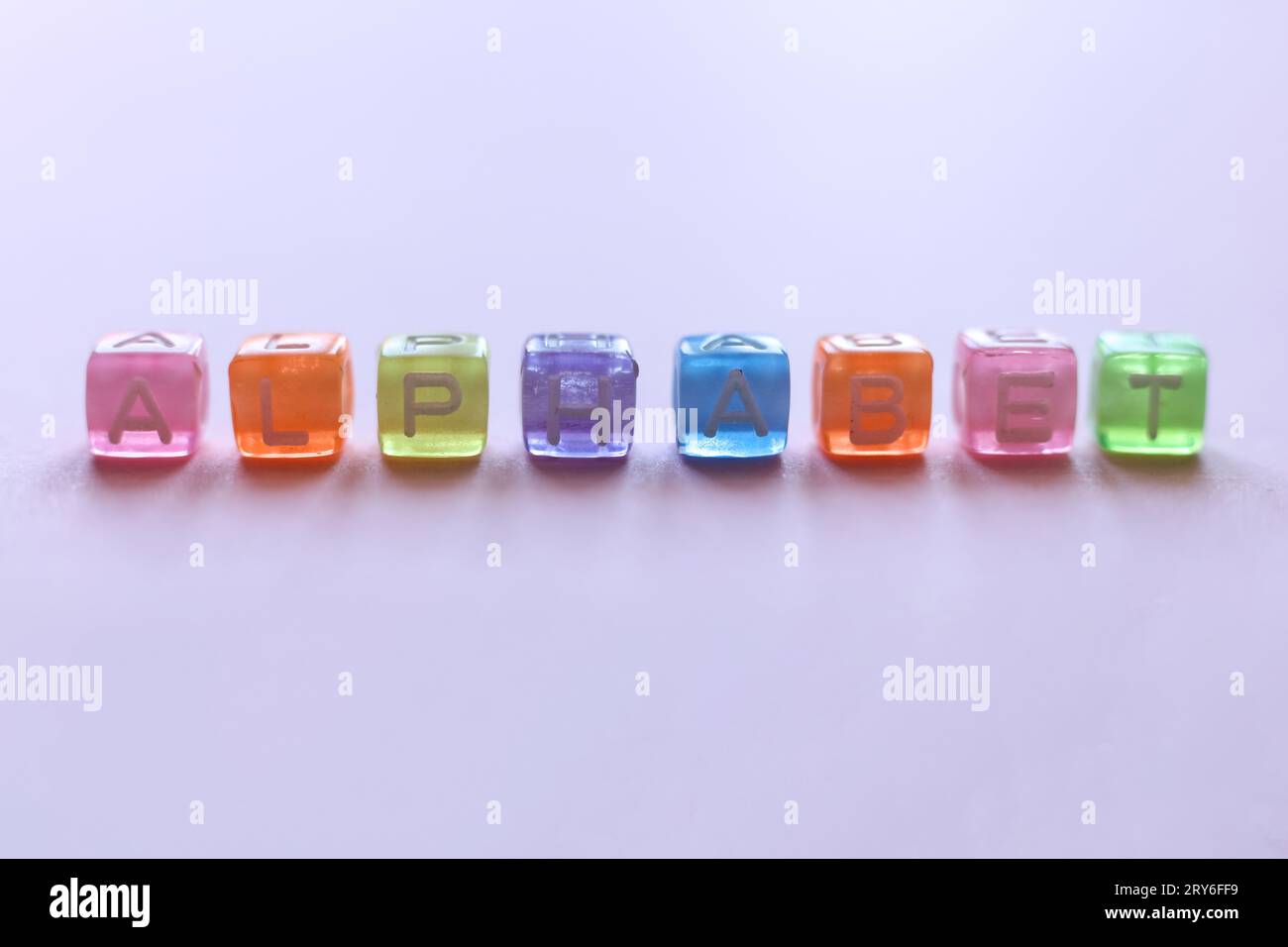 Makroaufnahme mit bunten Perlen, die das Wort Alphabet auf rosa Hintergrund buchstabieren Stockfoto