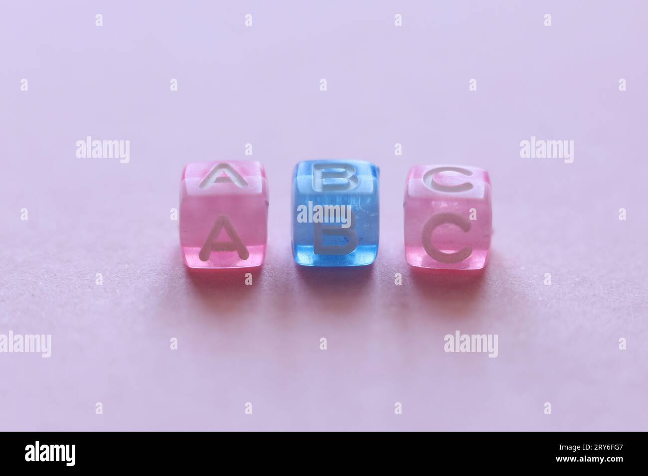 Makroaufnahme mit rosafarbenen und blauen Perlen mit der Schreibweise abc auf rosafarbenem Hintergrund Stockfoto