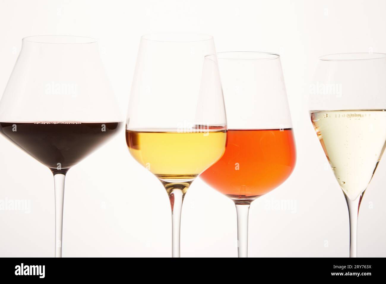 Rosafarbene, weiße, rote, prickelnde alkoholische Getränke in Weingläsern. Stockfoto