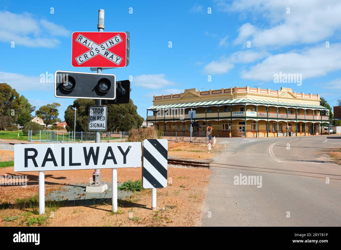Eine Bahnüberfahrt und ein Schild mit der Exchange Tavern im Hintergrund in der Landstadt Pingelly, Wheatbelt Region, Western Australia. Stockfoto