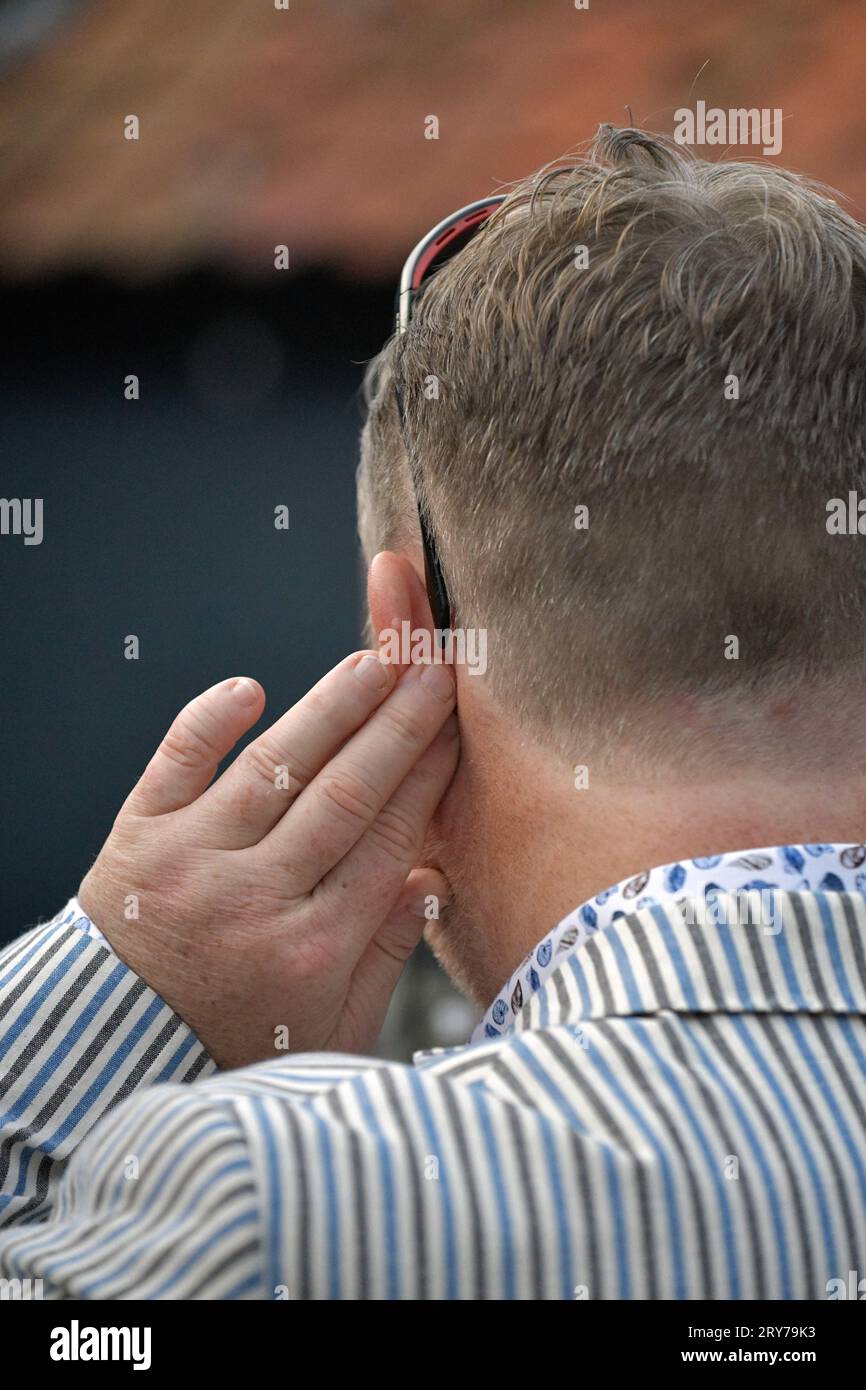 Mann, der die Hand hält, um besser zu hören, Stockfoto